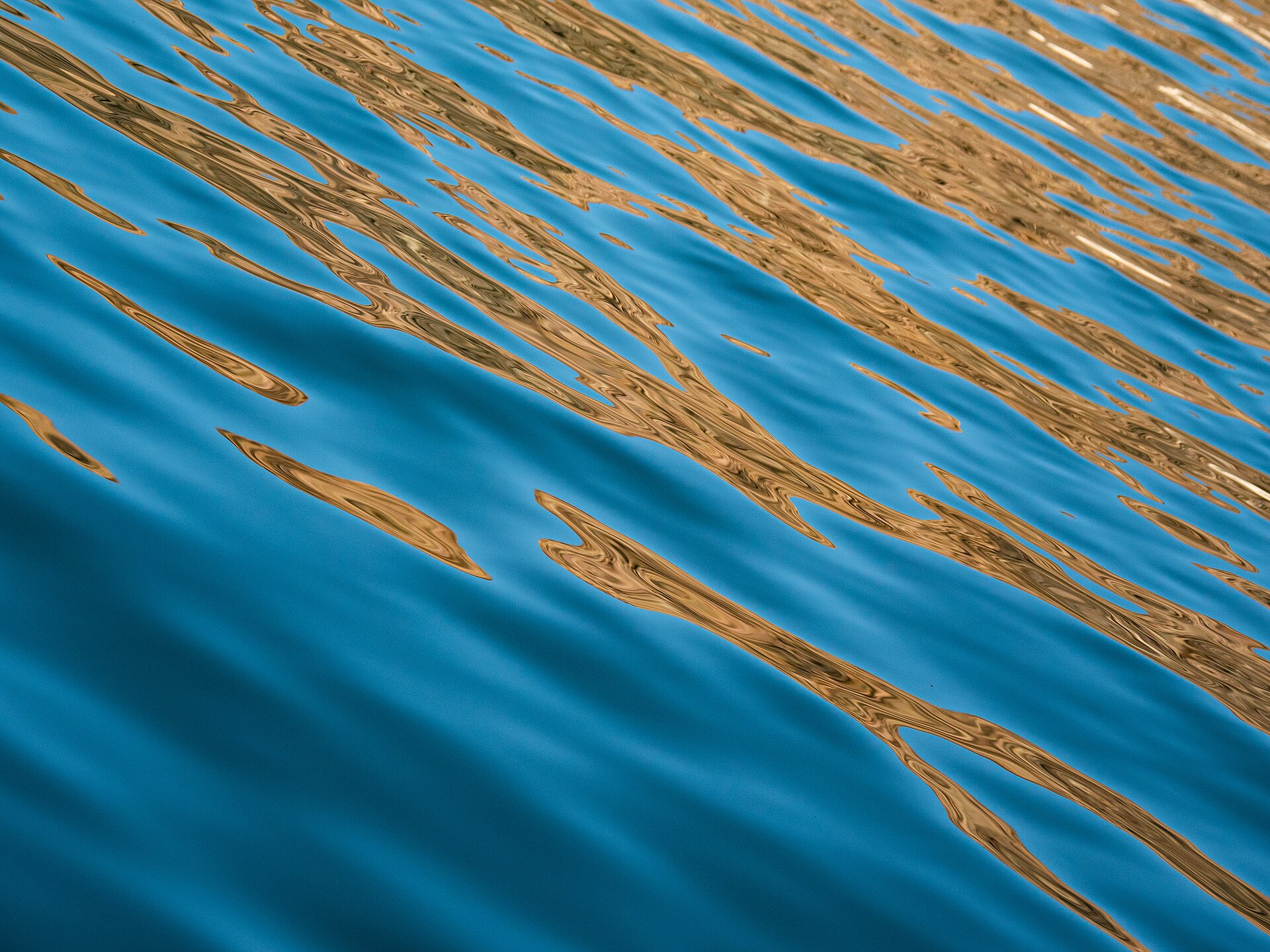 Calm Lake Mead waters reflecting sky and red canyon walls at dawn.